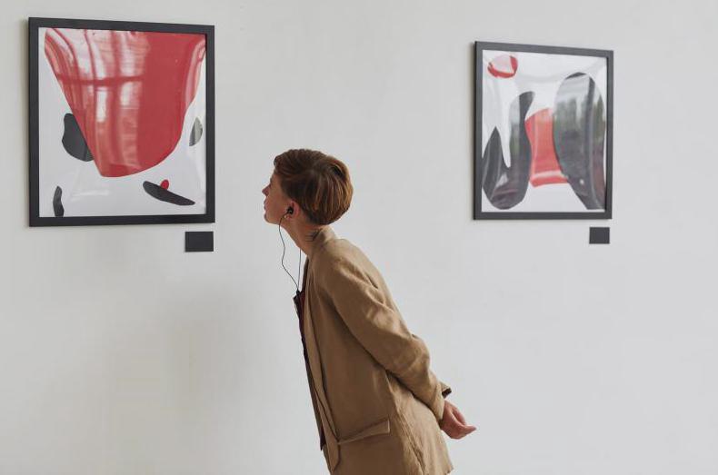 giovane donna che guarda i dipinti ascoltando l'audioguida mostra della galleria d'arte moderna